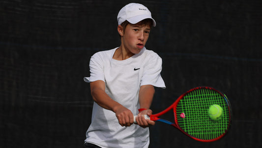 Boy, with UTR Rating, wearing white Nike hat and white Nike shirt hits a backhand while playing tennis