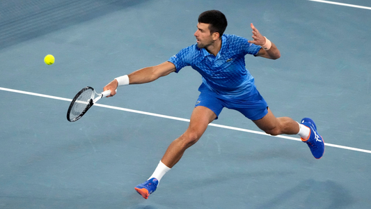 Novak Djokovic stretches for a backhand volley.