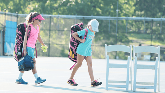 Two young girls walk onto a tennis court for a Little Mo tournament match.