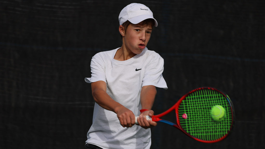 Boy, with UTR Rating, wearing white Nike hat and white Nike shirt hits a backhand while playing tennis