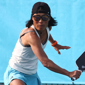 A man in athletic wear serves a pickleball on an outdoor court, focused and ready for the game.