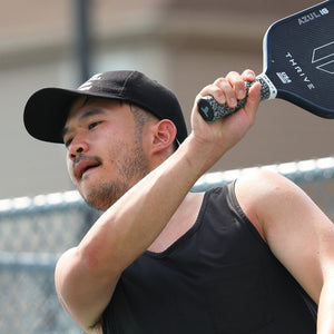 Man holding a pickleball paddle with a blurred background