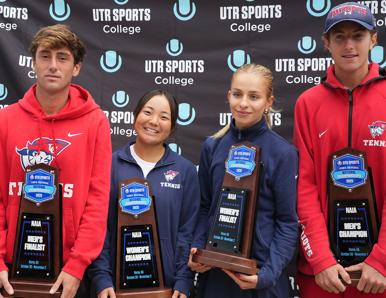 Four UTR Sports players standing together and holding NAIA championships trophies in front of a black UTR Sports College backdrop.